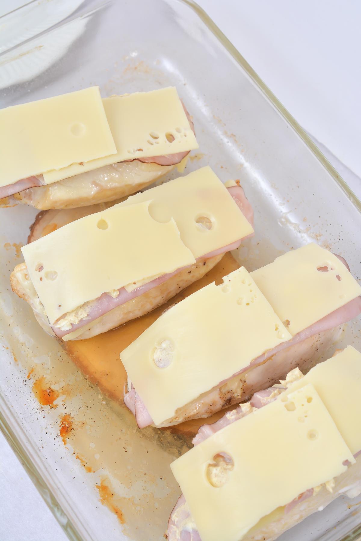 Slices of Swiss Cheese are added on top of the ham and chicken breast.