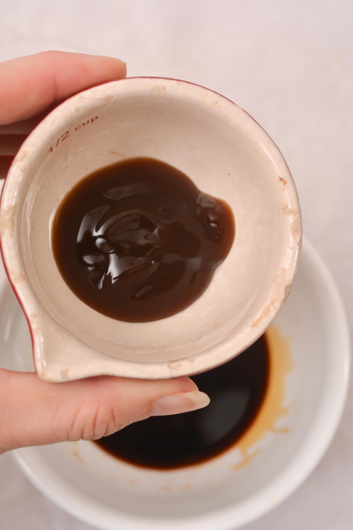 A person holding a bowl of oyster sauce.