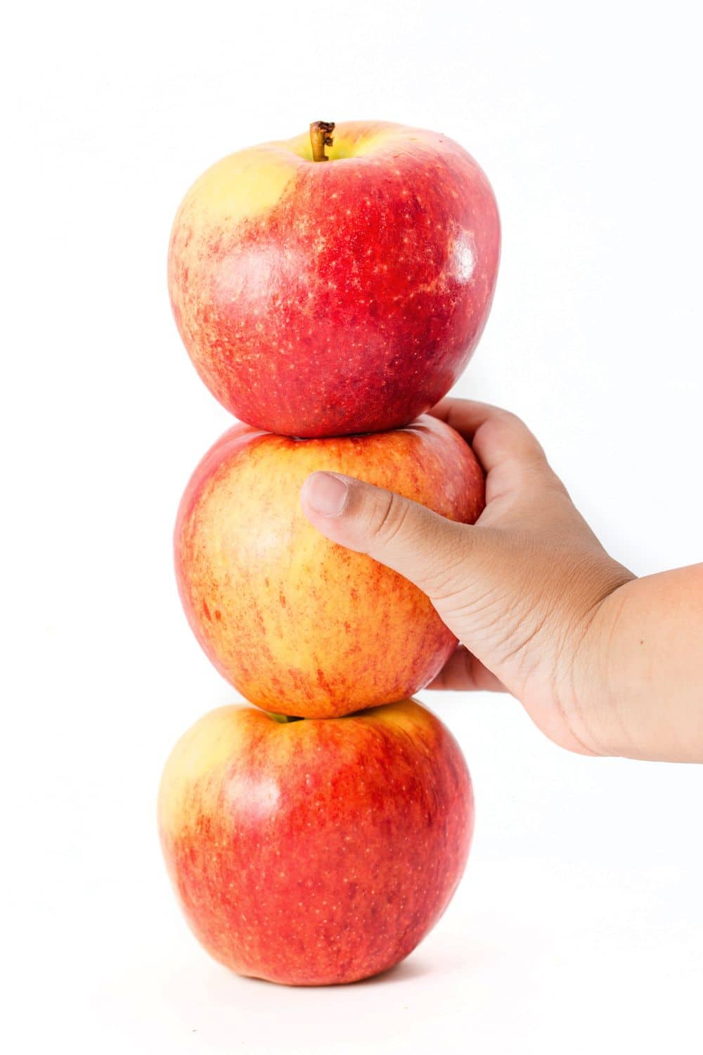 A hand holding a stack of apples, perfect for minute to win it games for kids.
