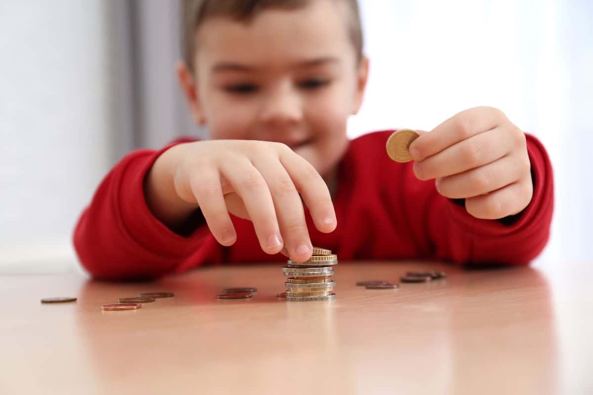 In a "minute to win it" game, a young boy focuses on stacking coins on a table.
