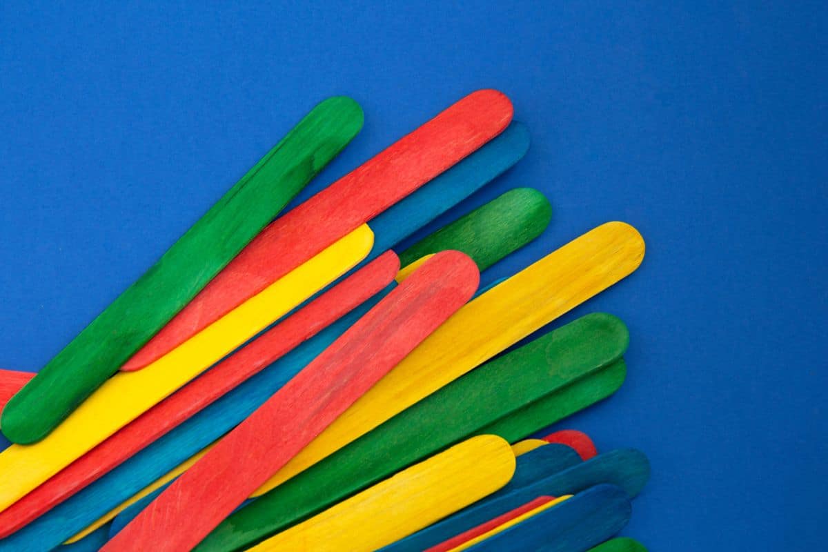 A pile of colorful popsicle sticks on a blue surface, perfect for minute to win it games for teens.