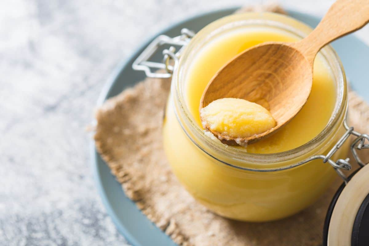 A jar of ghee with a wooden spoon, perfect as a canola oil alternative.