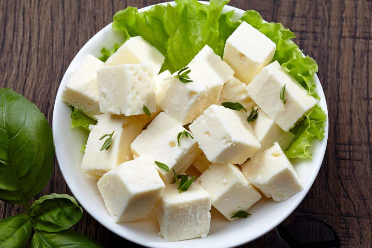 Cubes of feta cheese in a bowl on a wooden table.
