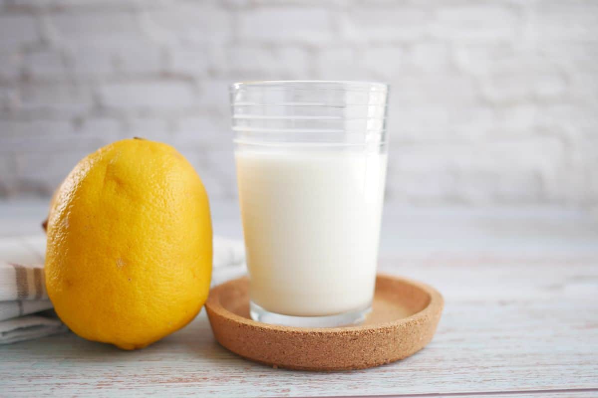 A glass of milk next to a lemon.