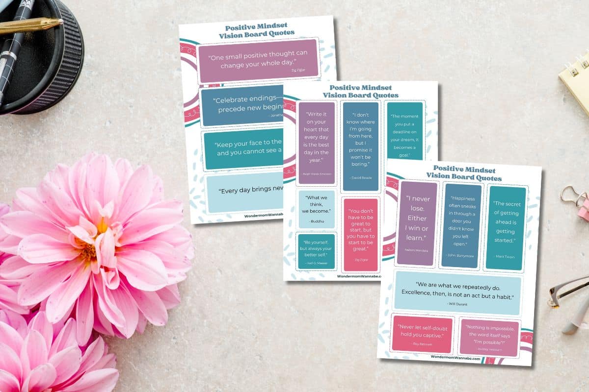Vision board quotes printables on a desk table with pink flowers.