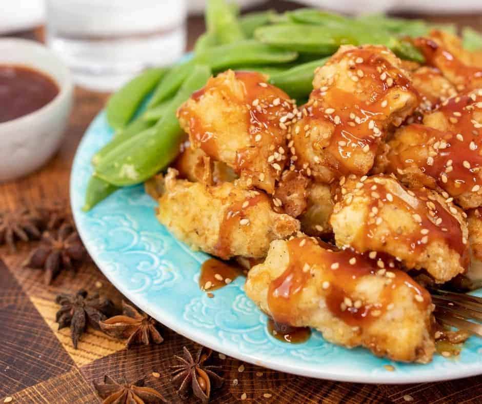 Asian chicken wings on a plate with green beans and sauce.