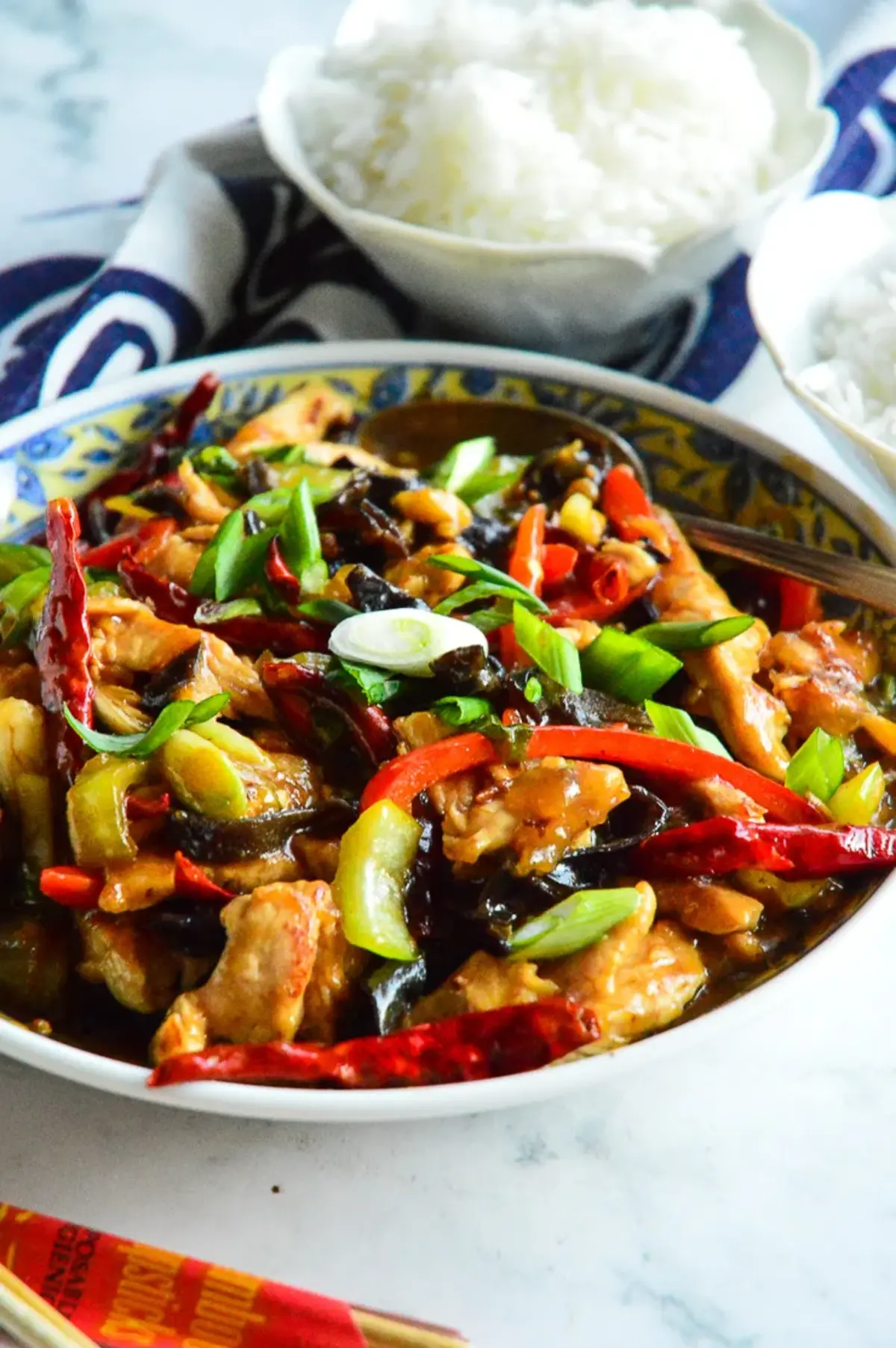 Chinese chicken stir fry in a bowl with rice and chopsticks.