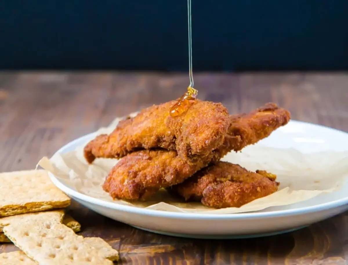 Fried chicken with honey and crackers on a plate.