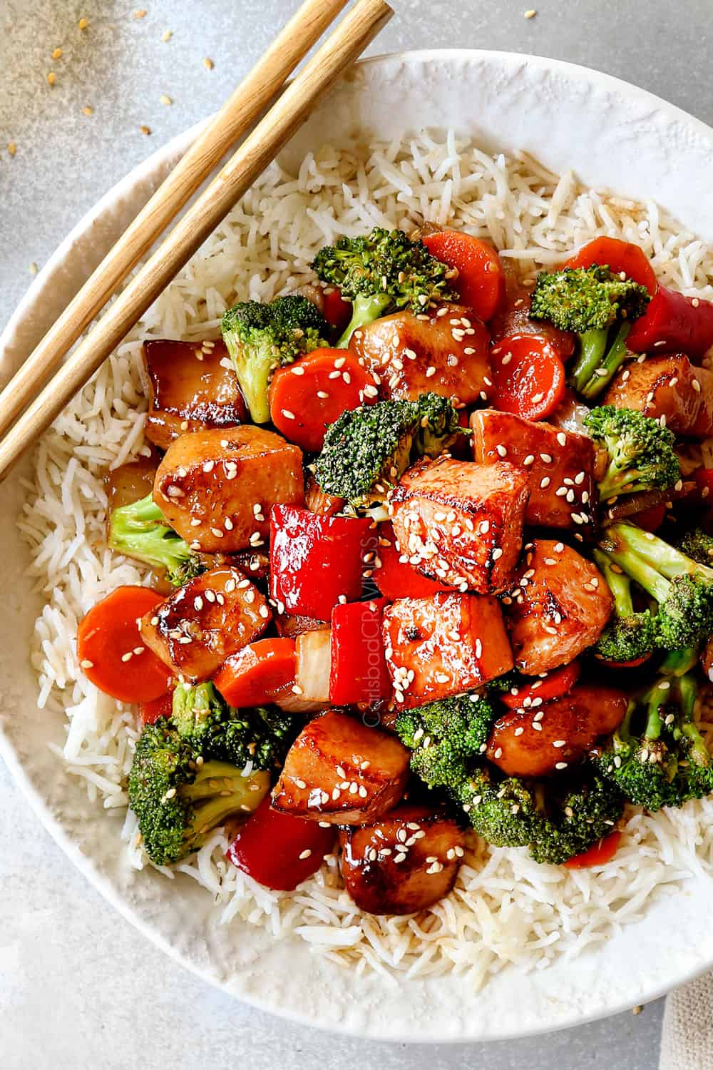Chicken and broccoli stir fry with rice and chopsticks.