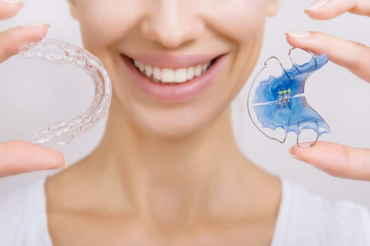 A woman holding a pair of retainers.