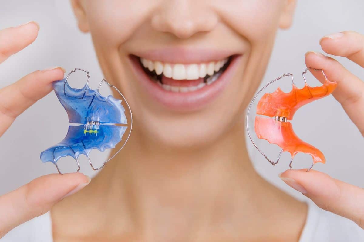 A woman is holding a pair of retainers.