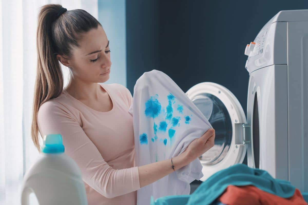 A woman holding a shirt with detergent stains on it, wondering how to get rid of them.
