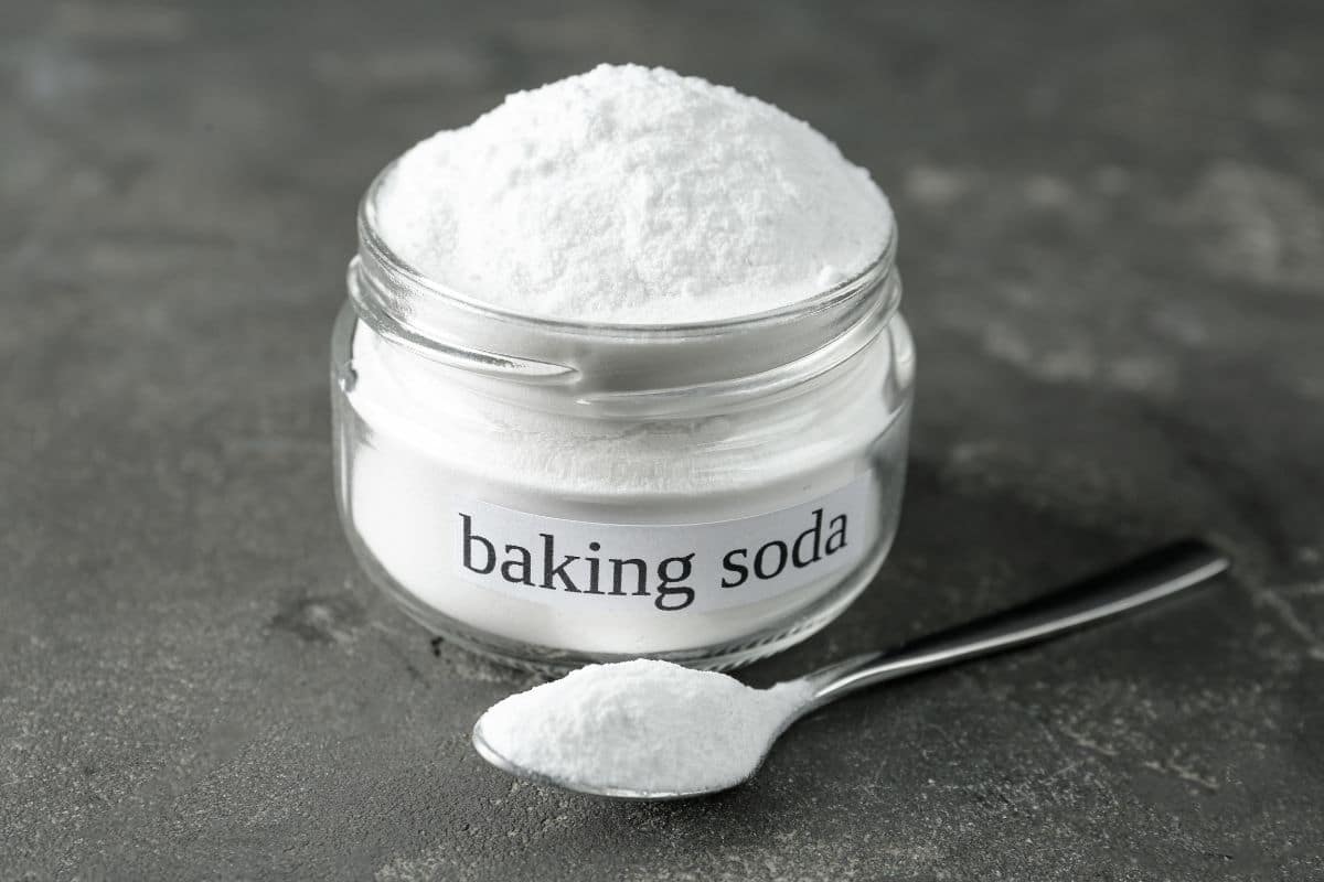 Baking soda in a jar with a spoon for removing milk stains from carpet.