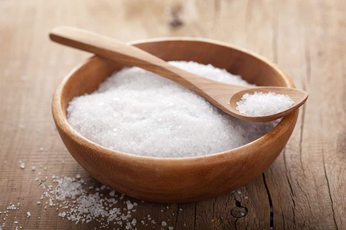 Salt in a wooden bowl on a table, used for removing tea stains from carpet.