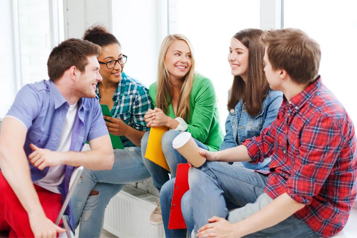 A group of young people sitting together in a room, engaging in Icebreaker Games for Teens.