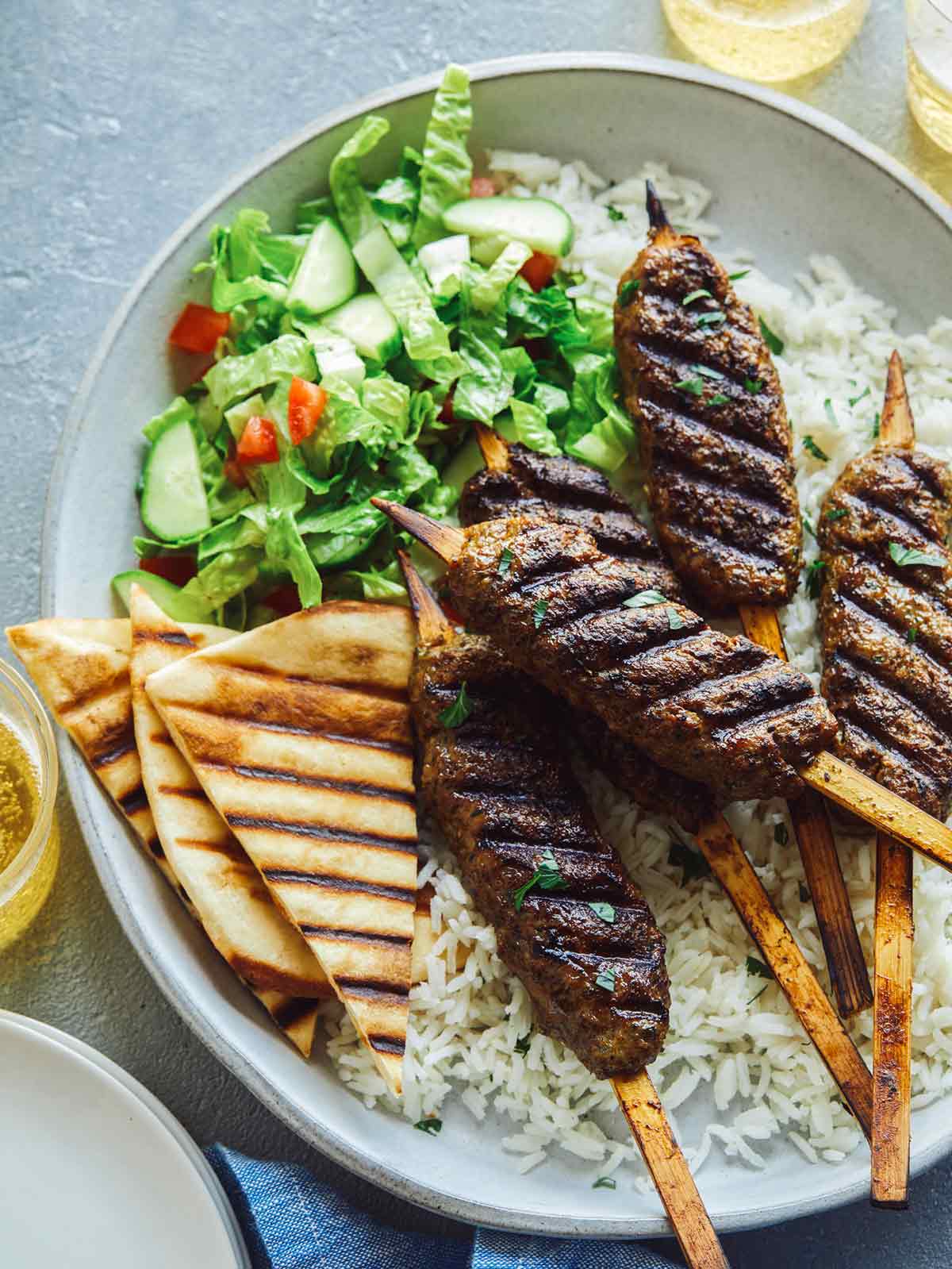 Kebabs on skewers with salad on a plate.
