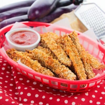 Panko-crusted eggplant fries served in a basket with a savory dipping sauce.
