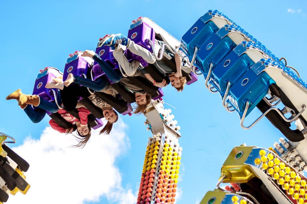 A group of teens riding a roller coaster at an amusement park.