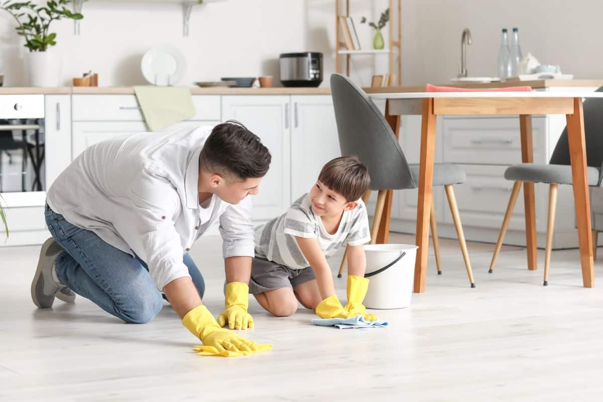 Father and son cleaning the floor in the kitchen.