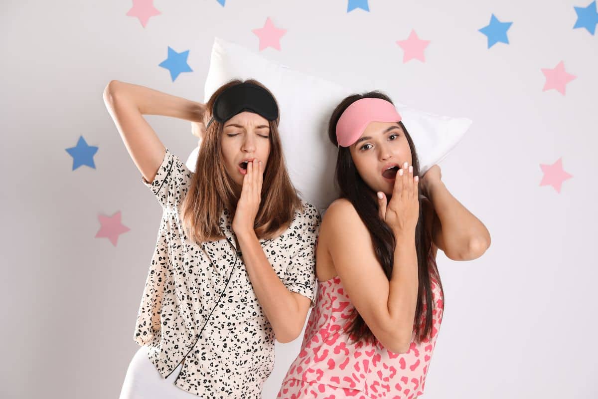 Two young women posing in a sleepover themed DIY photobooth.