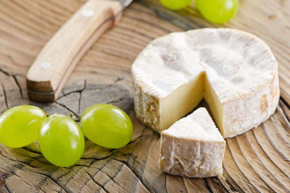 Camembert Cheese with grapes on a wooden table.