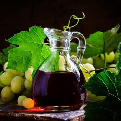 An alternative for sherry vinegar is a pitcher of wine and grapes on a wooden table.