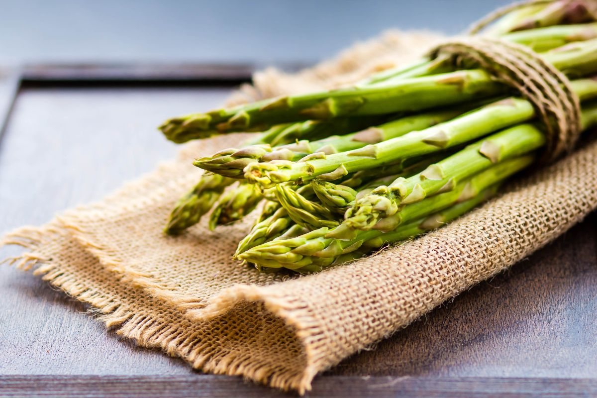 A bundle of green asparagus, a substitute for celery, on a wooden table.
