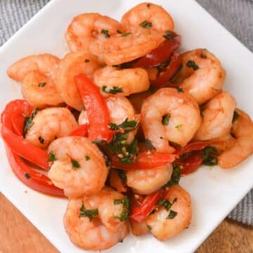 Thai Basil Shrimp plated with peppers in a simplistic white presentation.