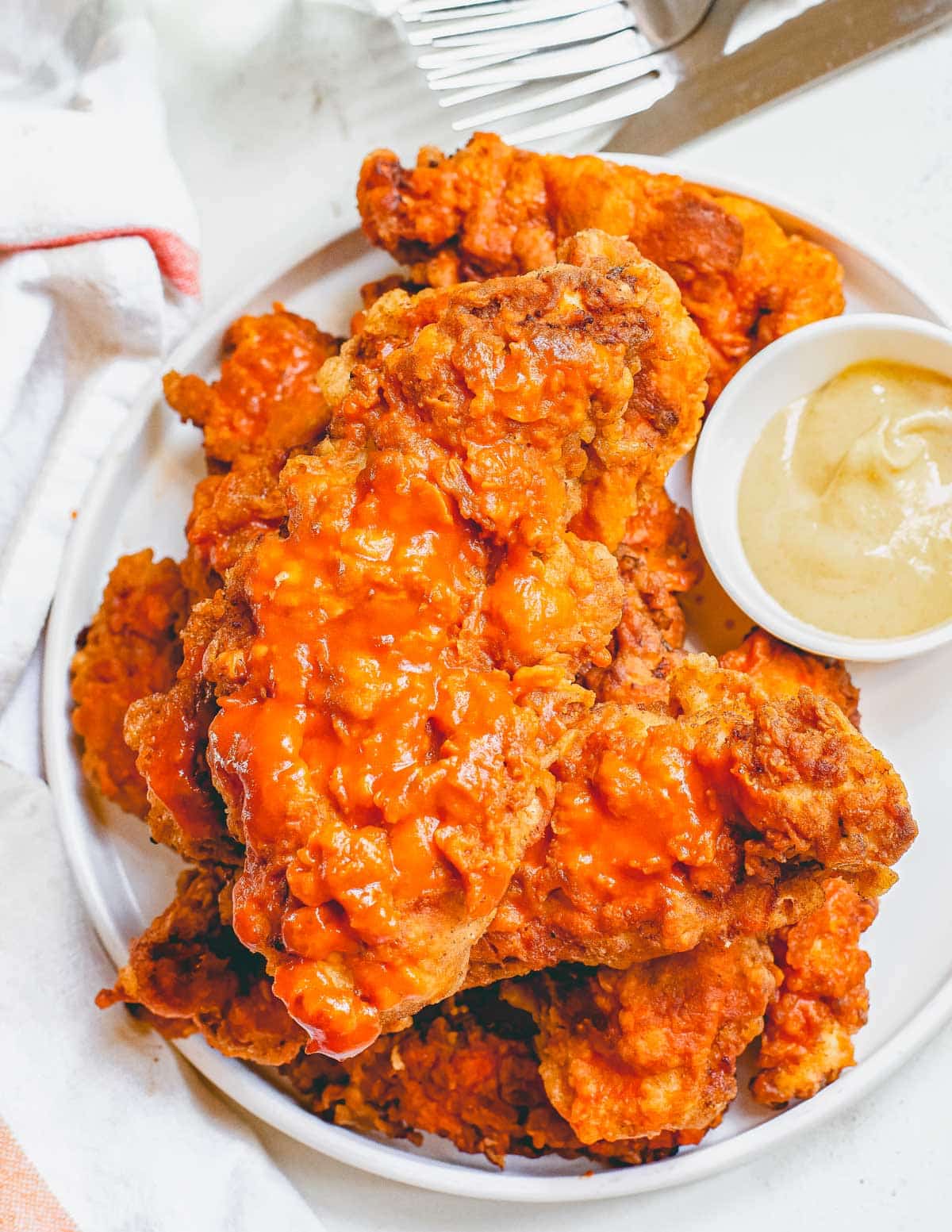 Fried chicken on a plate with sauce and a fork.
