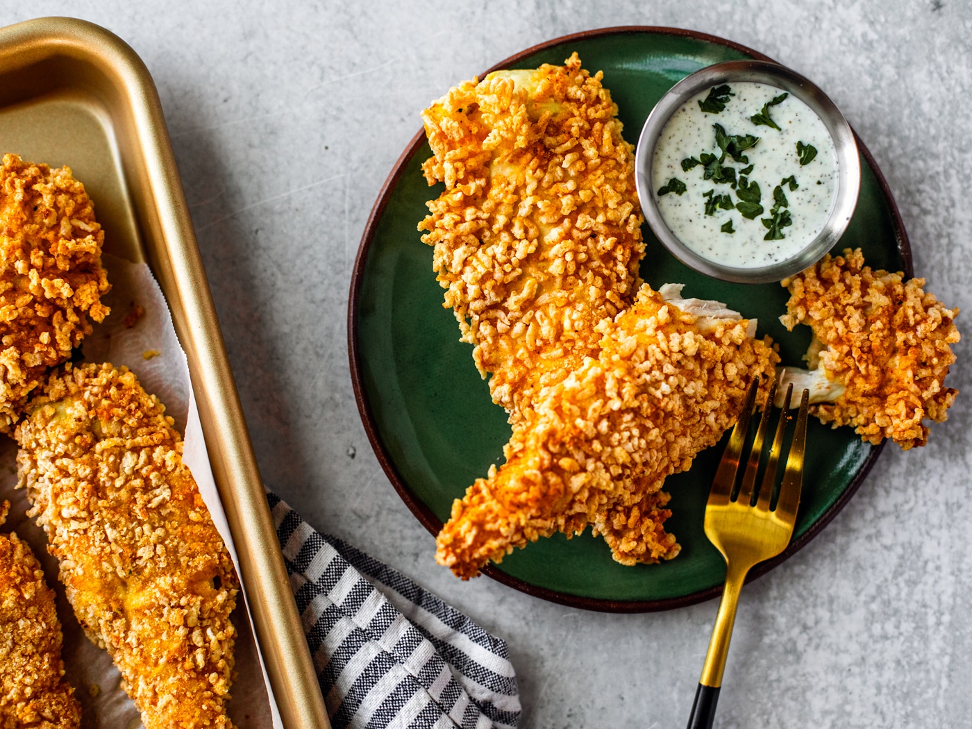 Fried chicken fingers with tzatziki sauce on a plate.