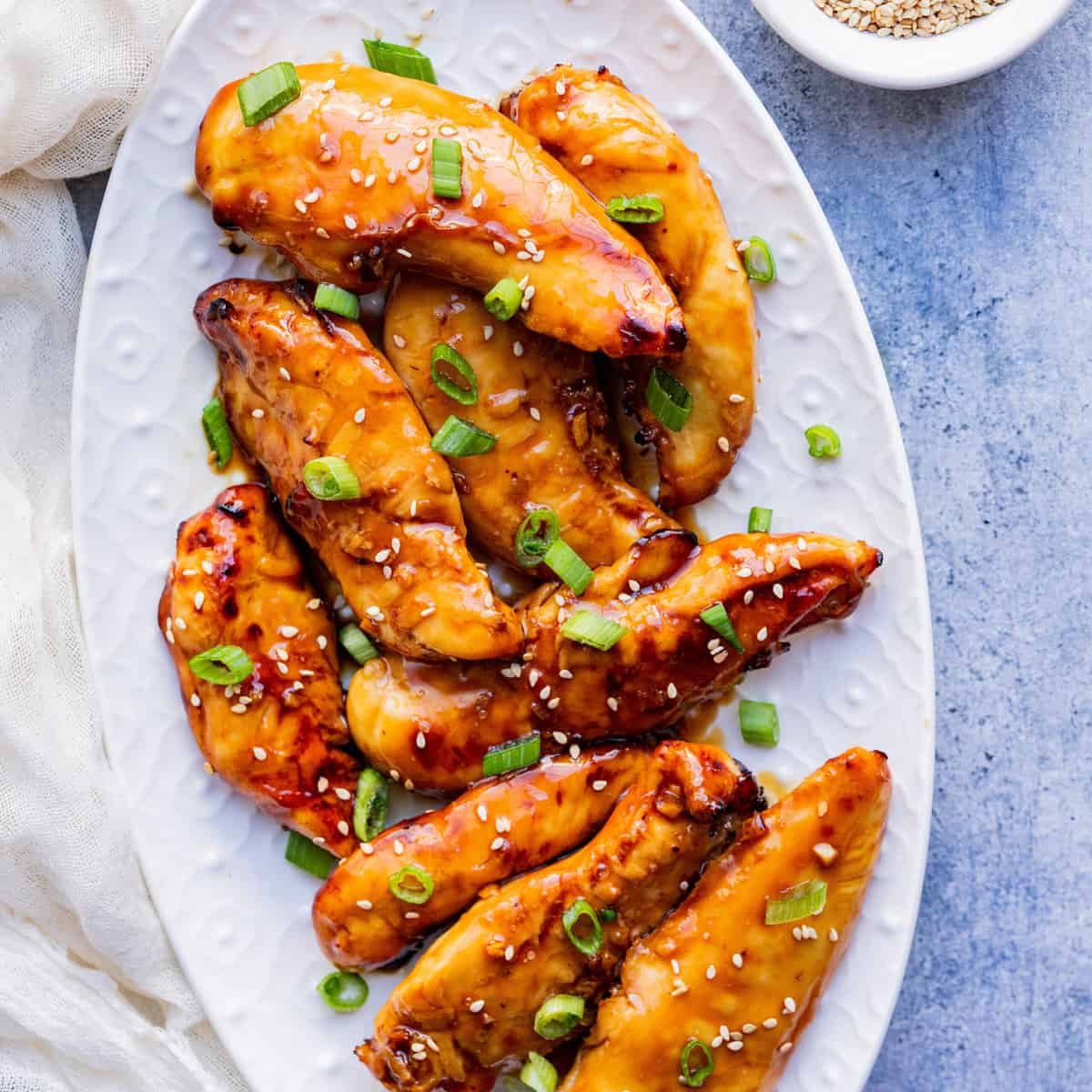 Asian chicken wings on a white plate with sesame seeds.