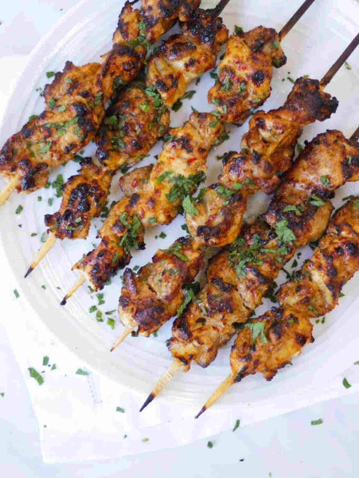 Chicken skewers on a white plate.