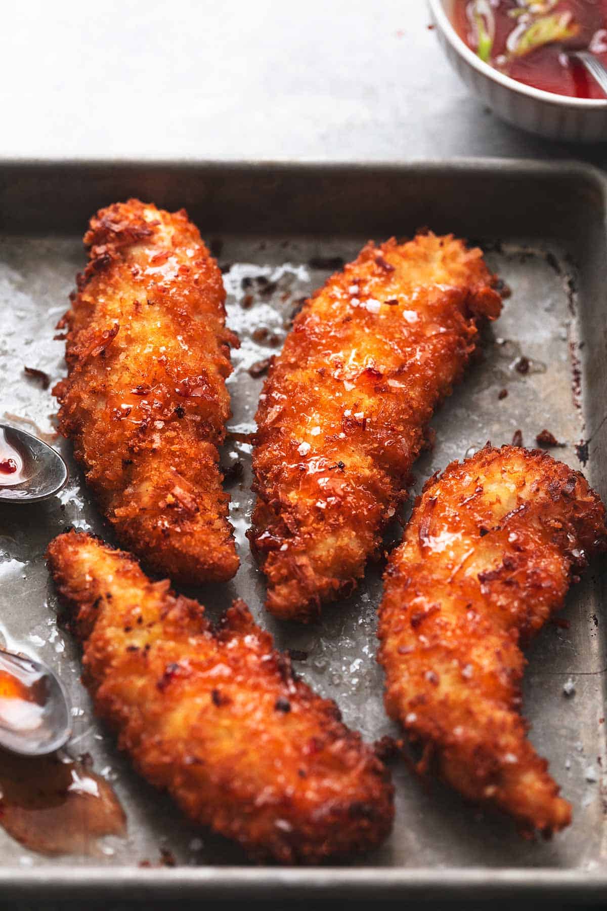 Fried chicken breasts on a baking sheet with sauce.