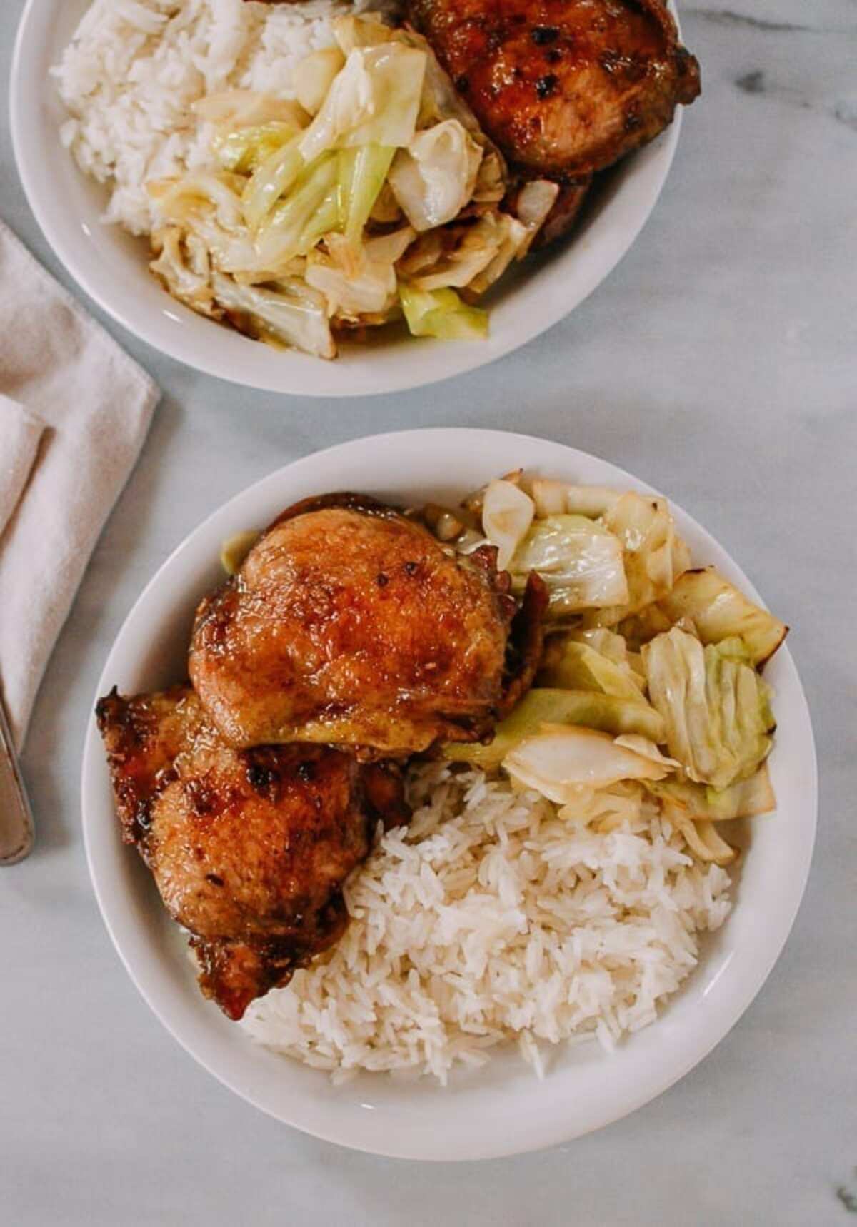 Two bowls of rice with chicken and cabbage.