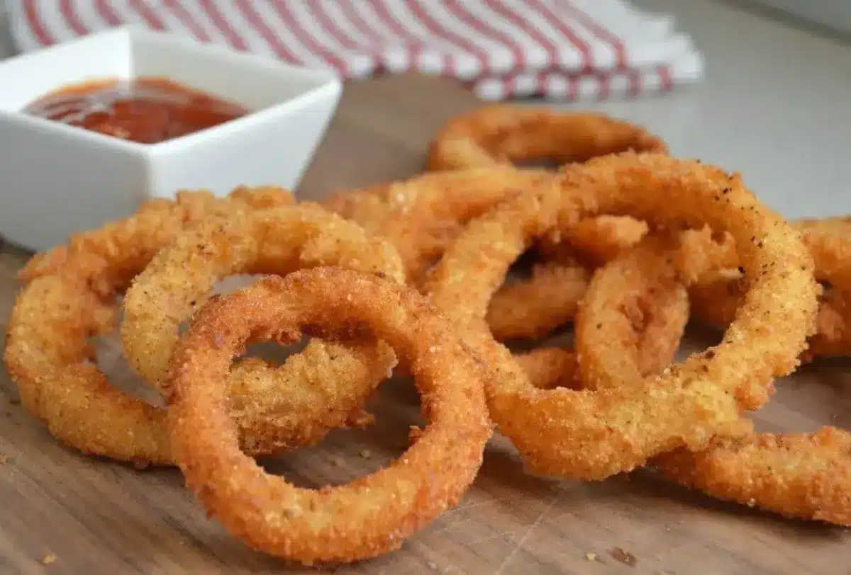 Onion rings on a cutting board with ketchup.