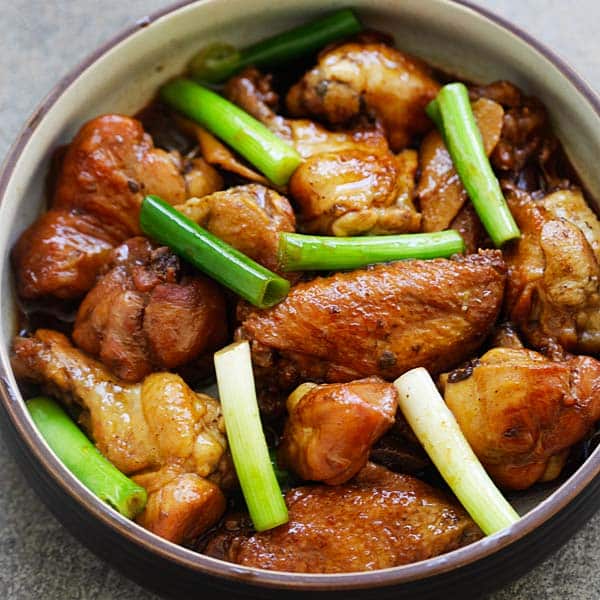 Chinese chicken in a bowl with green onions.
