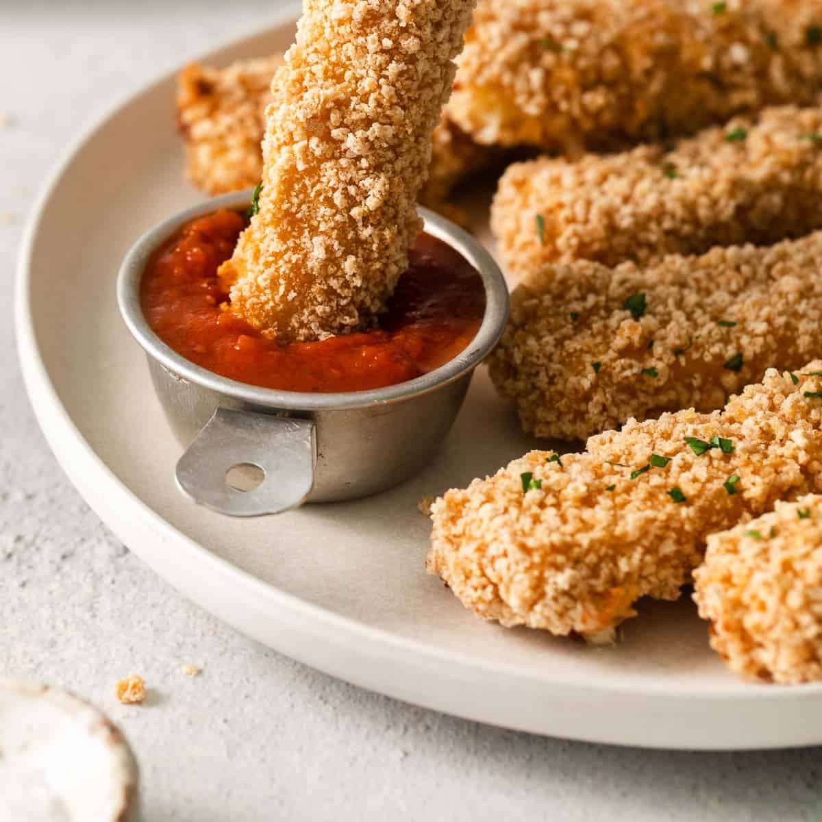 Fried bread sticks with sauce on a plate.