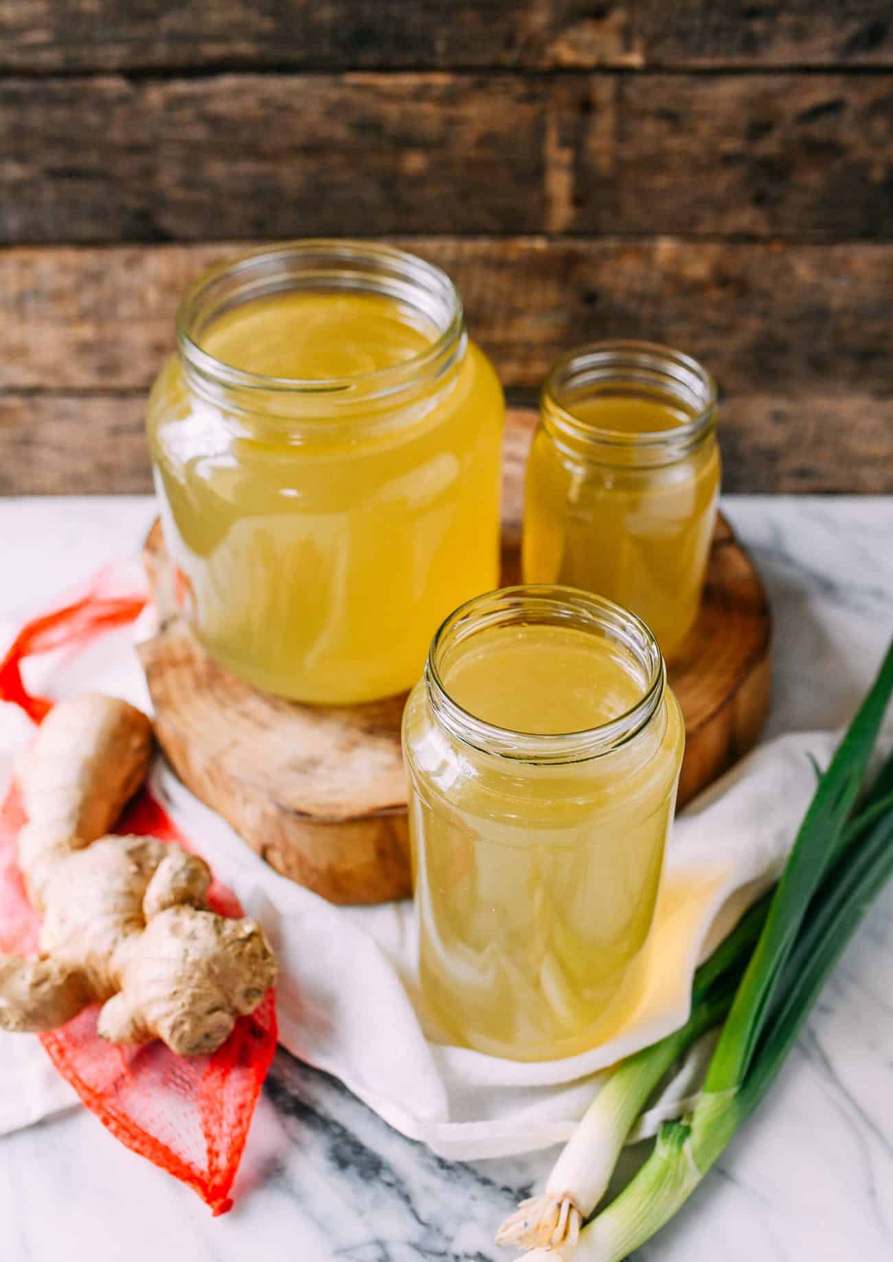 Two jars of ginger juice on a wooden board.