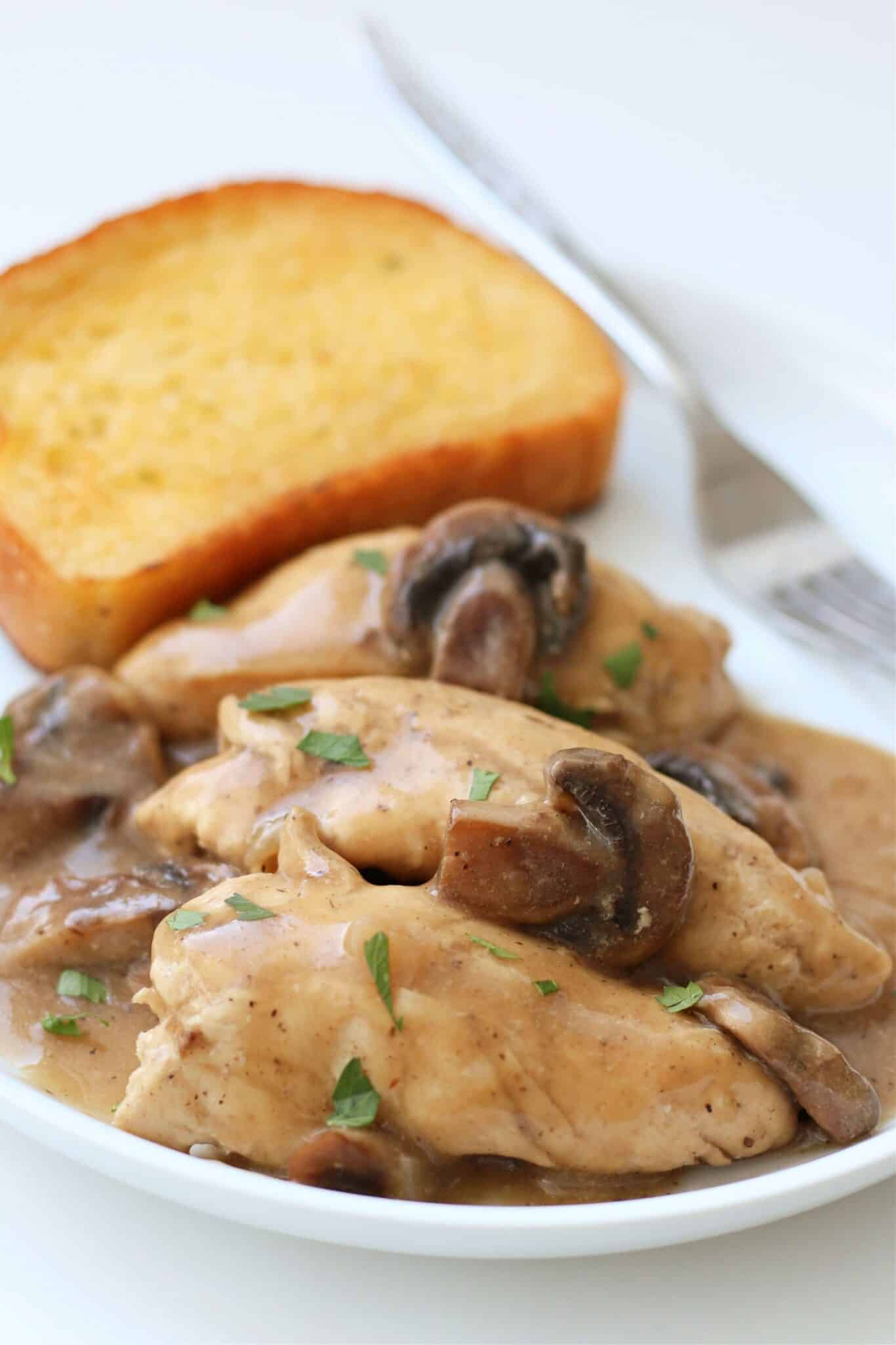 A white plate with mushrooms and bread on it.