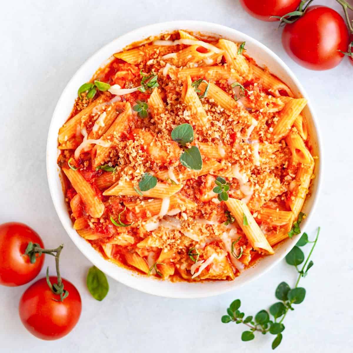 A bowl of pasta with tomatoes and herbs.