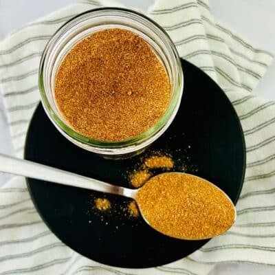 A jar of brown sugar sits next to a spoon, perfect for making a dry rub for pork.