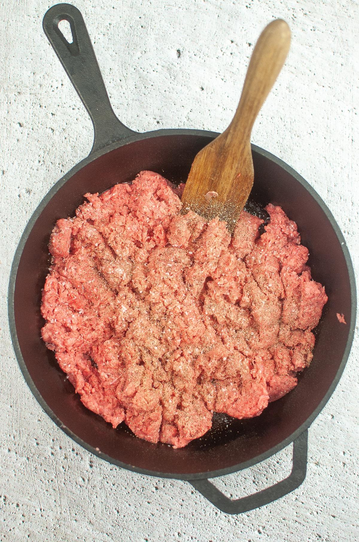 Salt and pepper are added to the ground beef.