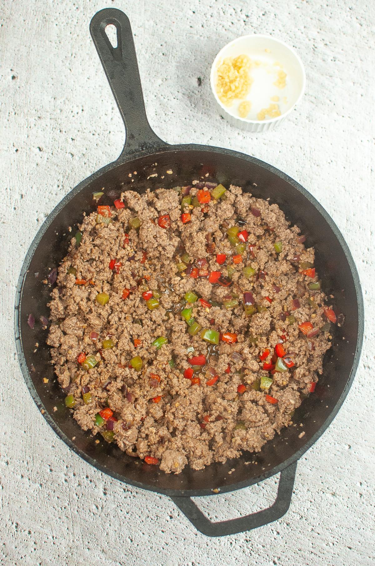 A dutch oven filled with ground beef and vegetables, simmering into a flavorful chili.