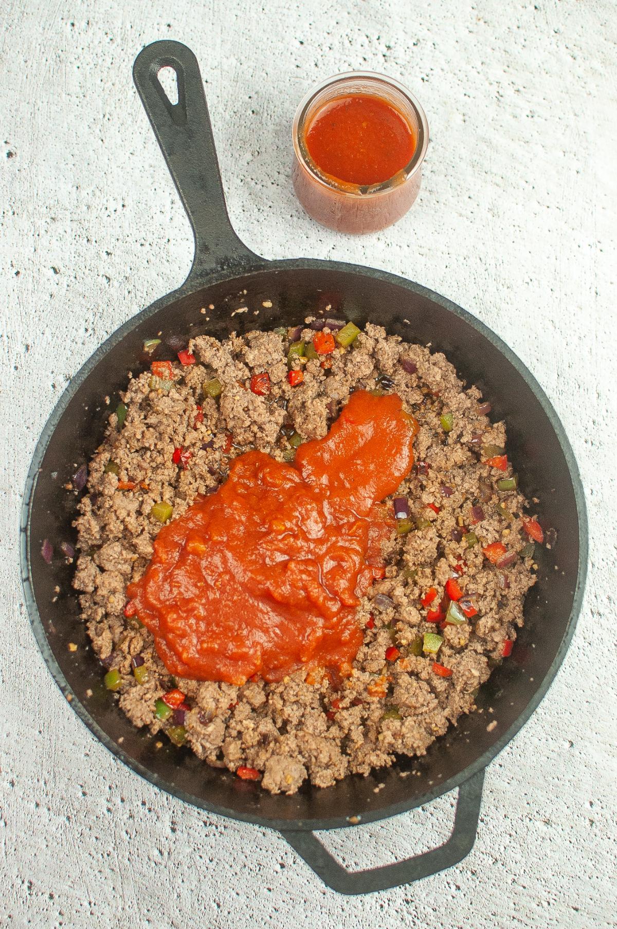 A tomato sauce is added to the ground beef mixture.