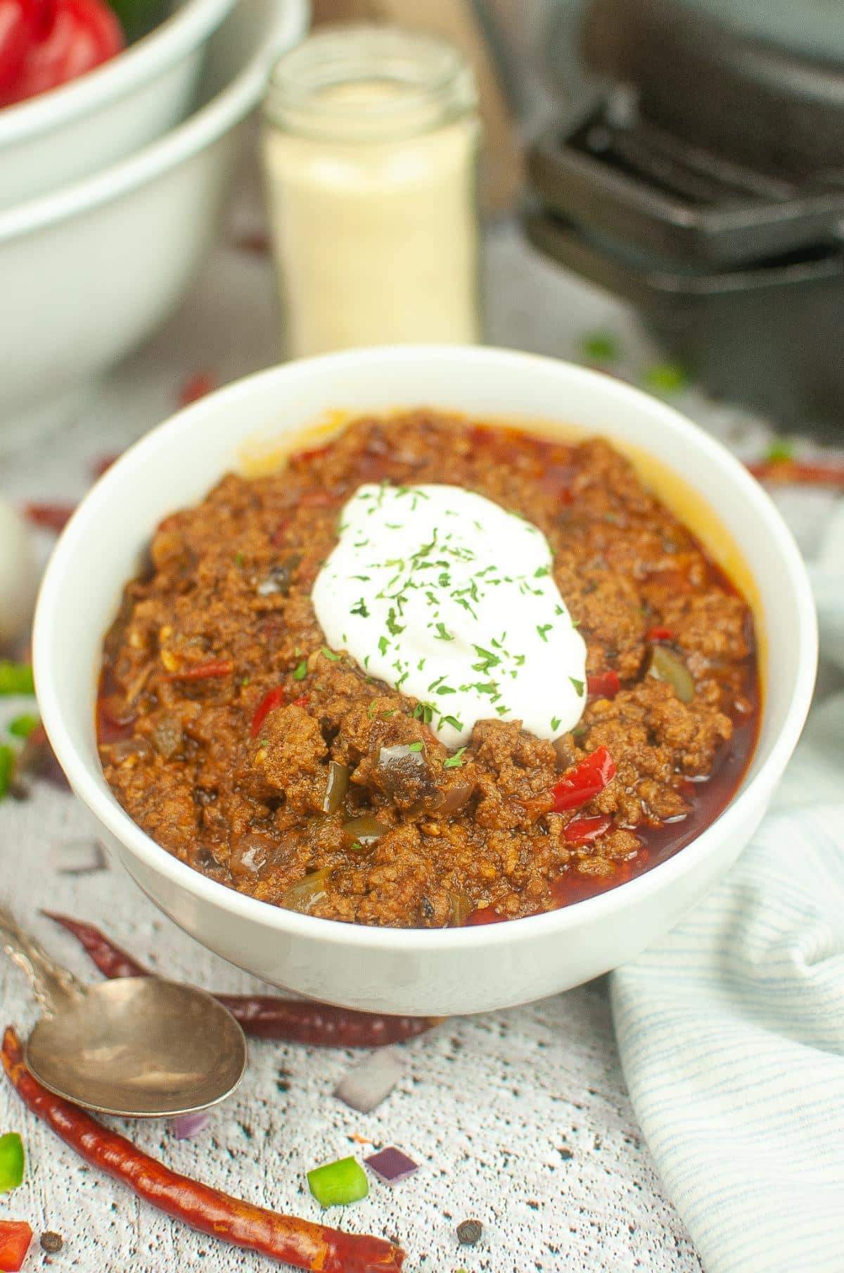 Dutch oven chili in a serving bowl, topped with a dollop of sour cream.