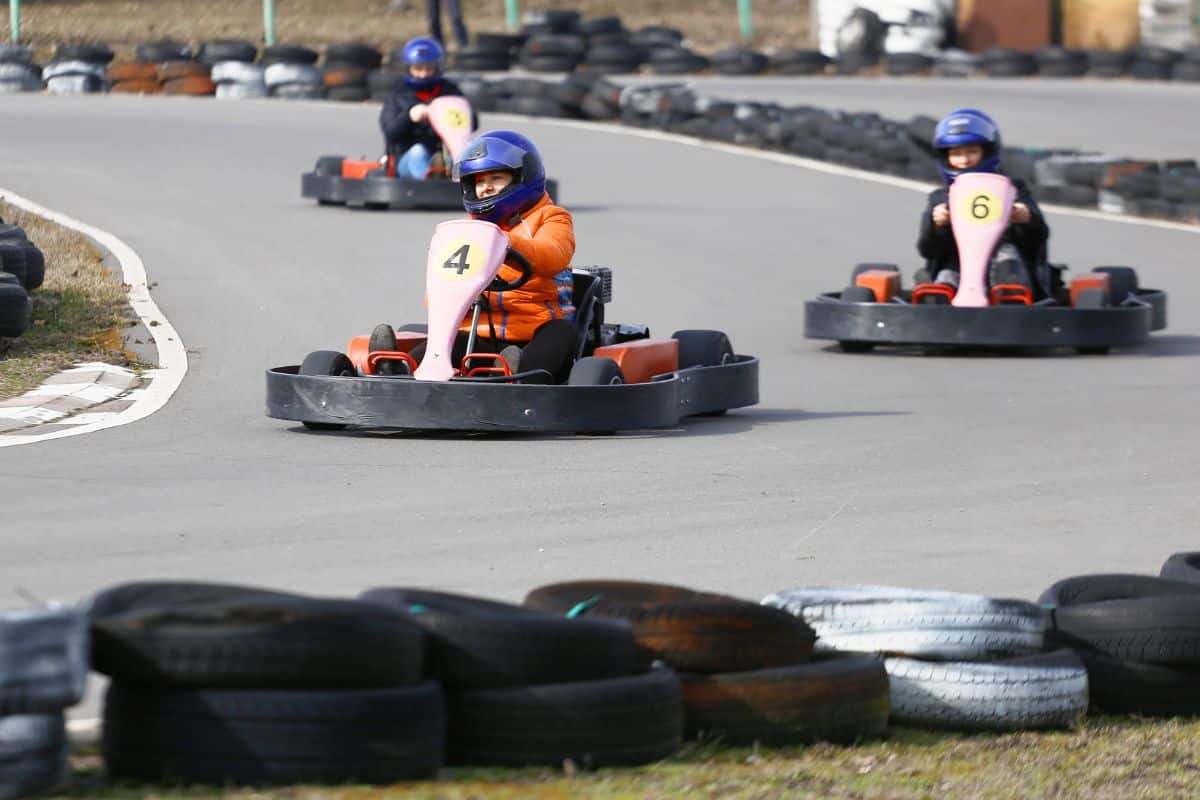 A group of teenagers driving go karts on a track, enjoying a fun activity together.