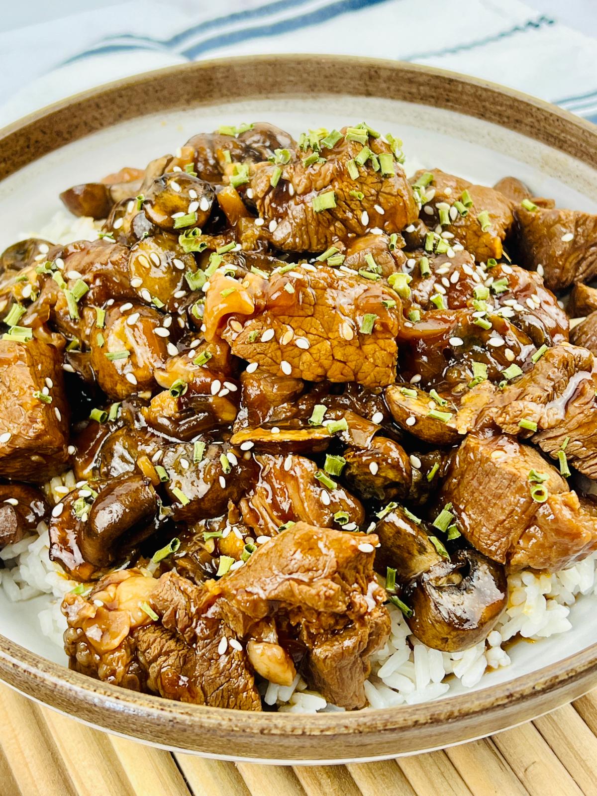A bowl of Korean beef stew with sesame seeds and spring onions over rice.