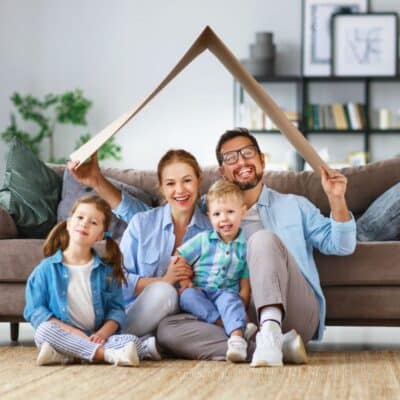 A family sitting on the couch, practicing safety rules at home with a cardboard house in front of them.