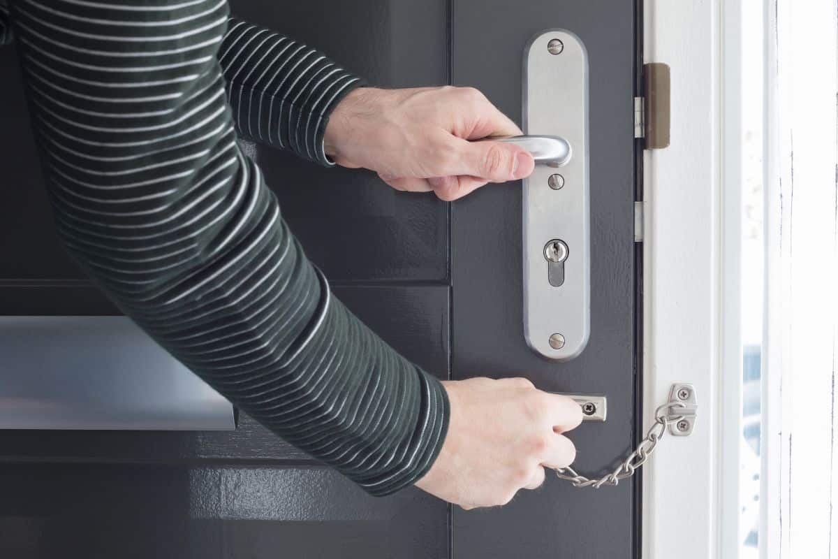 A person securing a door using a chain lock.