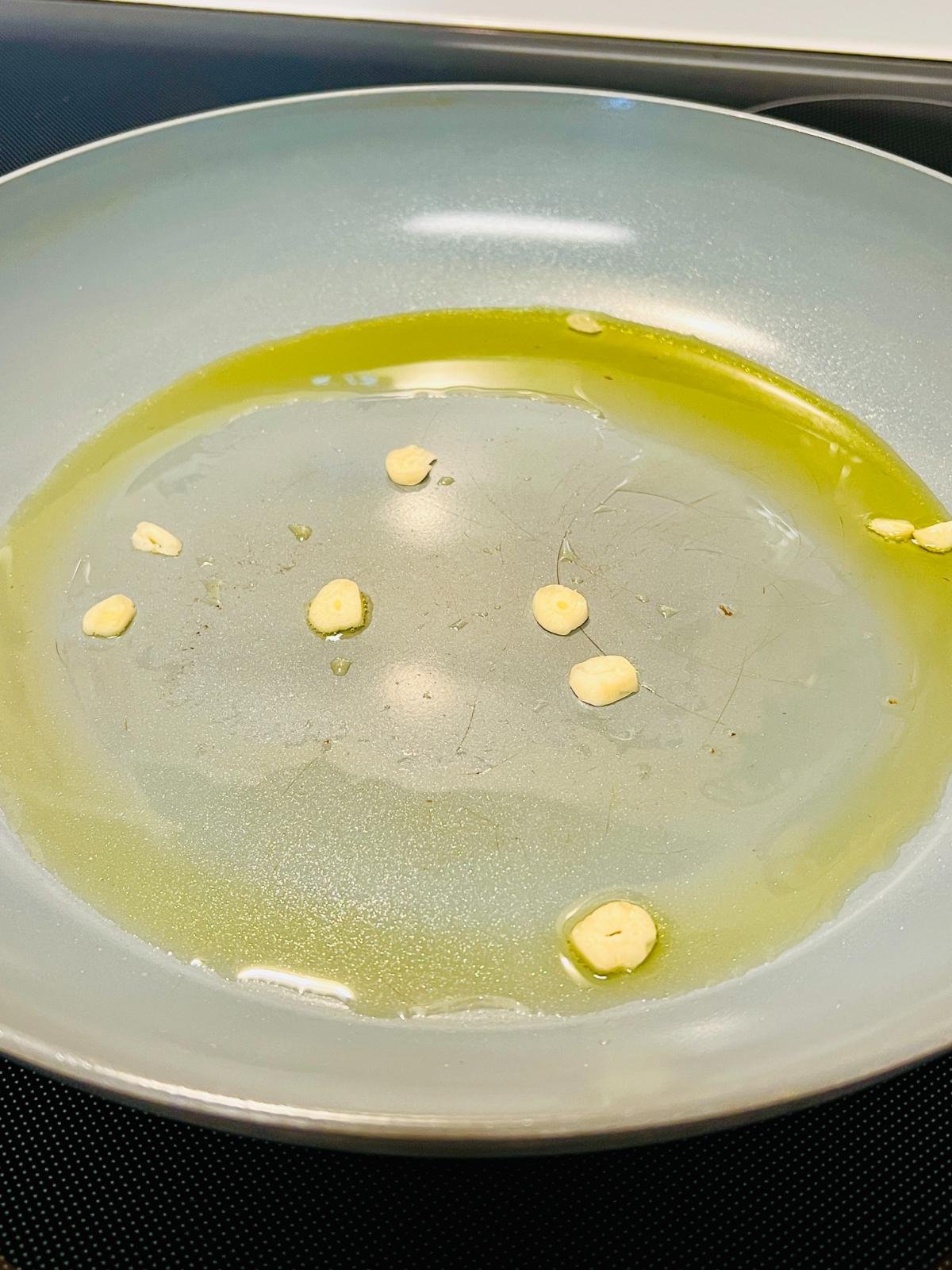 A close-up of a pan with olive oil and garlic.